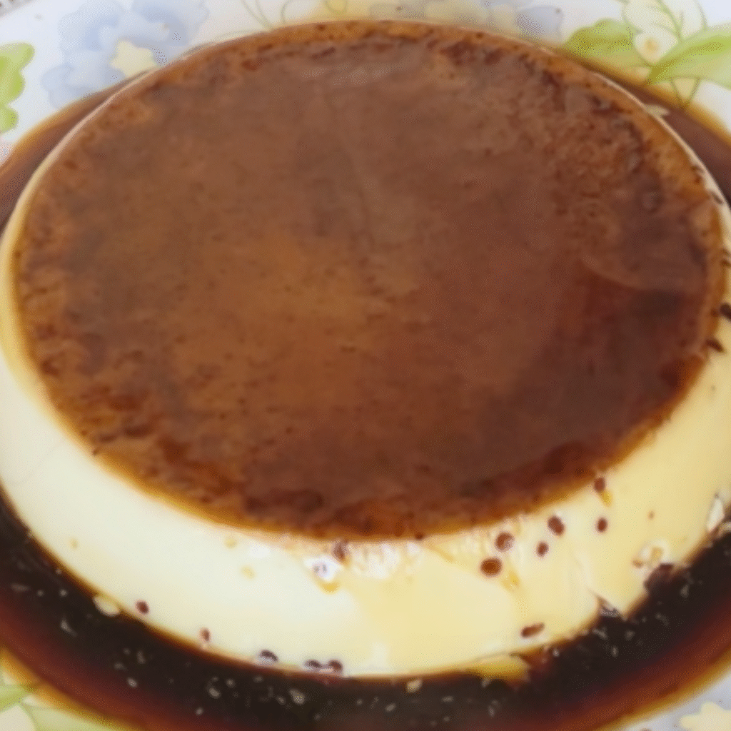 flan redondo cubierto de caramelo dorado en plato de ceramica con flores